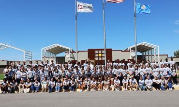 Students pose in front of campus for an orientation picture