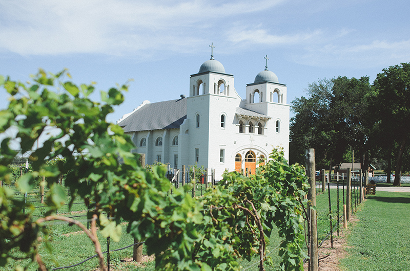 A white chapel surrounded by green trees and bushes