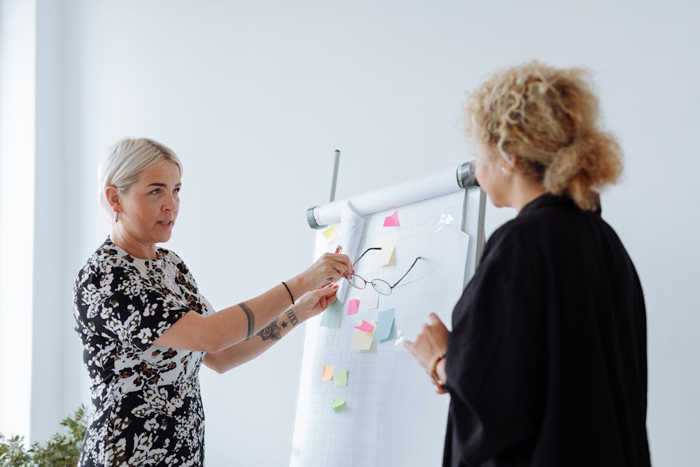 Woman in black and white floral print shirt points to example on large paper pad