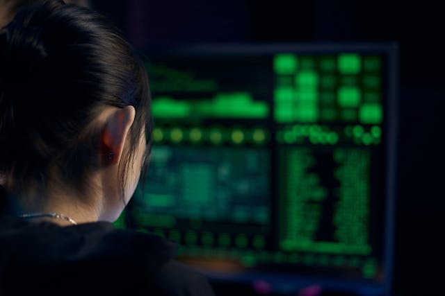 Woman with black hair stares at a computer screen filled with code