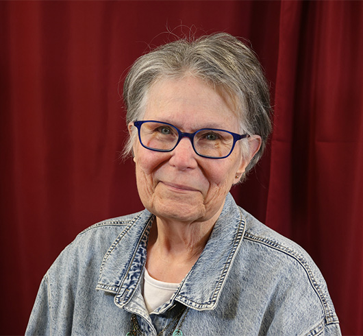 Woman with blue rimmed glasses wearing a jean jacket