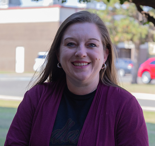 Woman wearing dark red cardigan over a Redlands tshirt