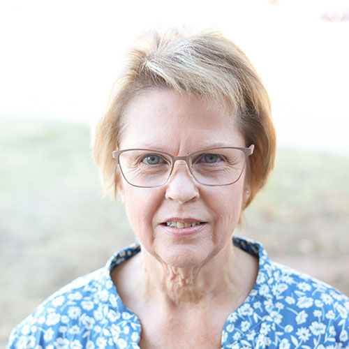 Woman with glasses in a patterned blue shirt with white flowers