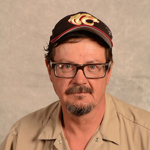 Man with a goatee and glasses wearing a hat