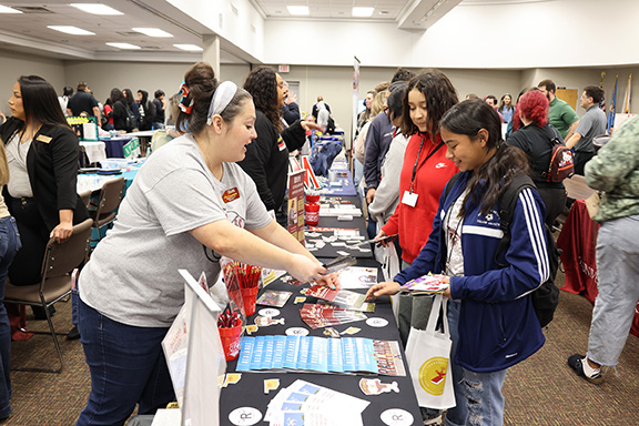 Woman shows college brochures to two female students