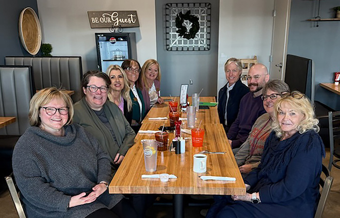 Eight people sit at a table eating lunch