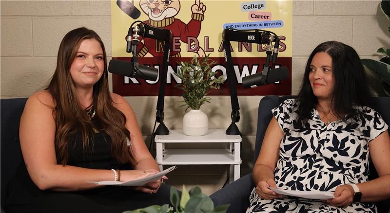 Woman in black dress sits next to a woman in a black and white patterned dress