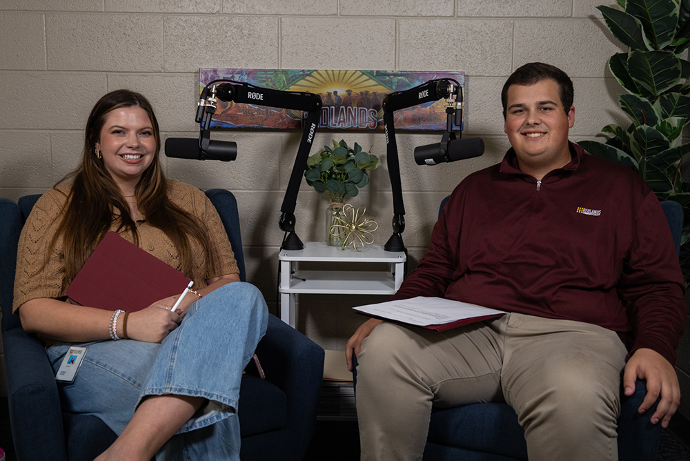 Woman in tan shirt smiles next to smiling man in dark red shirt