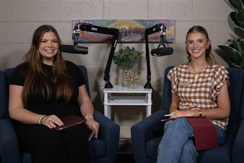 Woman in black shirt sits next to woman in red and white checked shirt