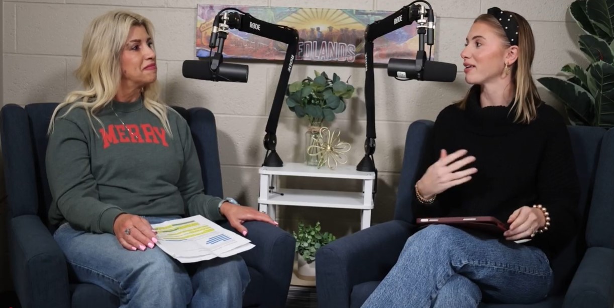 Woman with blond hair and a grey shirt sits next to woman with brown hair and a black shirt